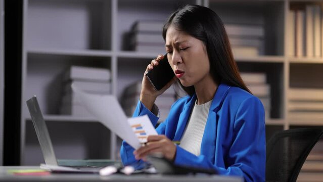 I dont want to hear excuses, just get it done. Serious Asian Businesswoman talking on mobile phone during a late night in the office.