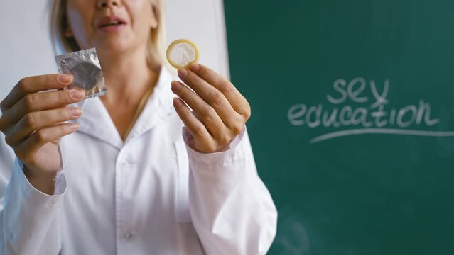 Teacher showing condom at lesson, importance of sex education and contraception