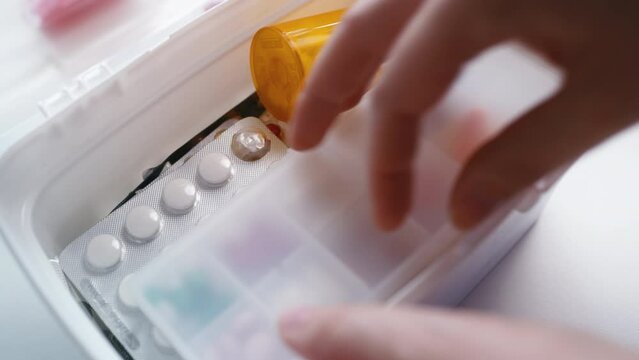Person putting medications into home medical kit, organizing first aid kit