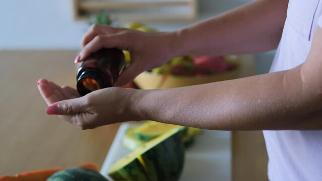Close-up of woman taking medicine from pill bottle by exotic tropical fruits, slow motion. Selective focus. Vitamins, nutritional supplements and healthy lifestyle concept
