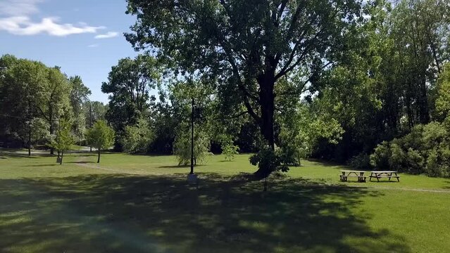 Drone flying over a green area in a park with lights and pic nic tables