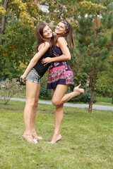 Obraz premium Two young beautiful sisters laughing and playing in park