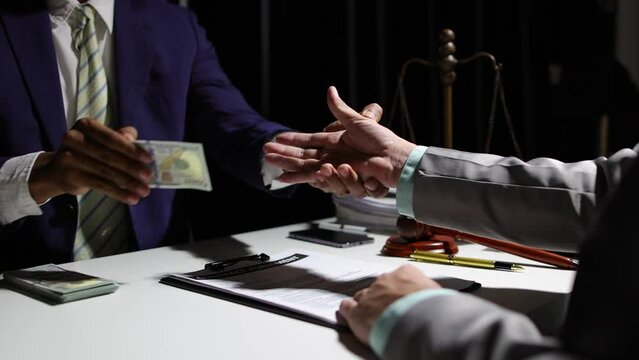 Corrupt lawyer accepts bribes from an unknown man in the dark. Businessman in the dark tries to bribe officials.
