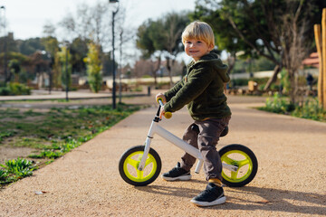 A little boy is on a bike ride.3 year old blond boy plays and enjoys a sunny day in the park on a bicycle