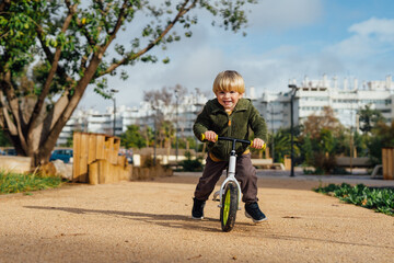 Obraz premium A little boy is on a bike ride.3 year old blond boy plays and enjoys a sunny day in the park on a bicycle