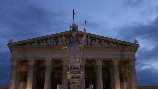 Vienna, Austria. Facade of the Austrian Parliament and Pallas Athene Fountain in the evening. Neoclassical style with columns and pediment like a Greek temple. Real time zoom in video. 2023-08-06.