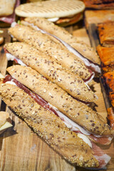 Seeded baguette sandwiches with ham and cheese on a wooden board.
