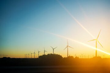 Sunset silhouette of wind turbines in a renewable energy landscape.