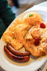 A hearty breakfast plate with French toast, scrambled eggs, and sausages.
