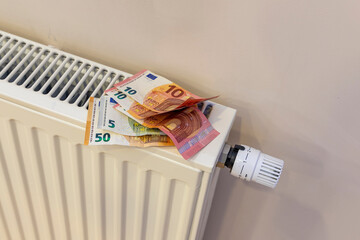 large sum of money in euros on a heating radiator. The concept of increasing prices for energy...