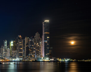 Obraz premium Panama City skyline at night next to rising moon at new year