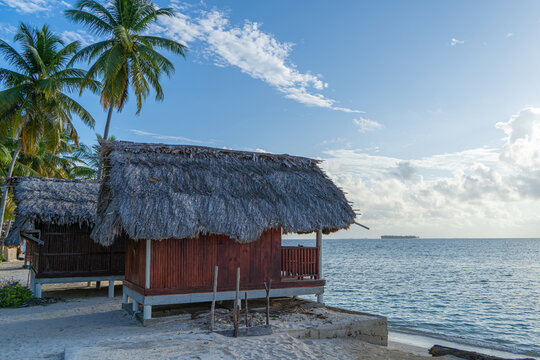 Red painted beach hut with palm trees at Panama bech on San Blas islands