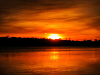 As the sun rose over the lake, the clouds in the sky turned orange and beautiful