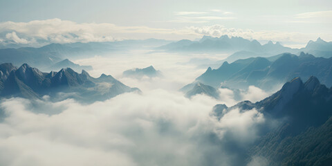 Misty Mountains: Majestic Scenery with Tranquil Valley, Foggy Peaks, and Snow-Covered Rocks against a Blue Sky.