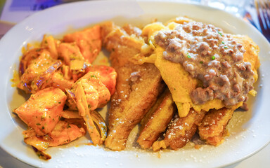 A hearty plate of fried chicken, waffles, gravy, and spiced potatoes.