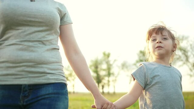 mother daughter walking in the park. happy family kid dream concept. close-up daughter holding her mother hand walking along the road sunlight in the park in nature. mom daughter outdoors in the park