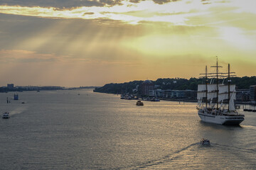 Obraz premium Luxury sailing yacht windjammer cruiseship cruise ship liner Spirit sail away under full sails from Hamburg, Germany on River Elbe during breathtaking sunset