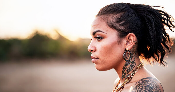 primo piano testa di giovane donna latino americana, vista di profilo, tatuaggi e capelli corvini