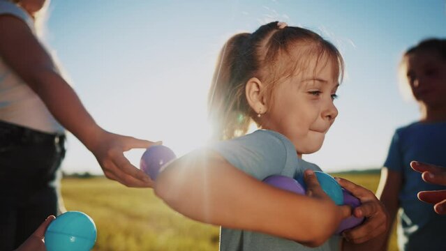 children conduct a relay race in nature in the park. happy family childhood dream concept. a group of little kids participate in a competition pass colorful balls to each other lifestyle