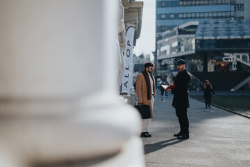 Obraz premium Stylish businessmen collaborate outdoors, conveying a successful partnership against the backdrop of a contemporary cityscape.