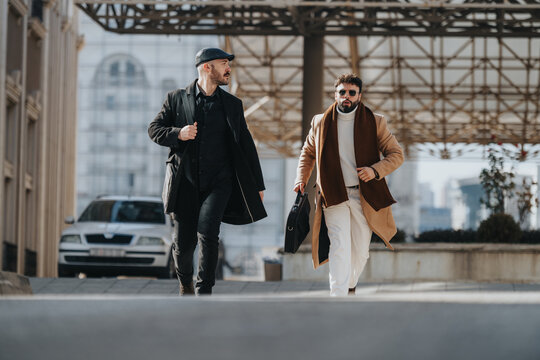Two stylish businessmen walking outdoors in the city on a sunny day.