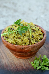 closeup the yellow fried rice with black month,brown ginger,green radish leaves in the wooden bowl soft focus natural grey brown background.