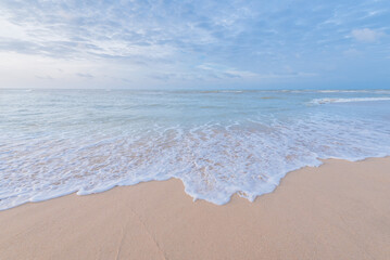 Soft wave of sea. sand beach seashore with blue wave and white foamy from blue sea in summer.