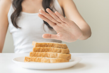 Gluten allergy, asian young woman hand push out, refusing to eat white bread slice on plate in...