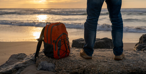 Man with backpack relaxing alone on the seaside on hot sunny day at sunset. Travel  Lifestyle...