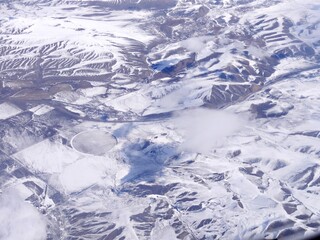Aerial view of the snow covered mountains and plains in the clouds