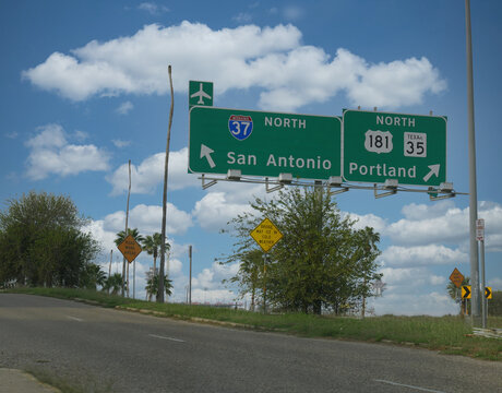 Directional signs with arrows to San Antonio and Portland in Texas.