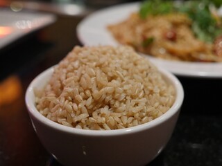 Small bowl of cooked, brown rice with blurred background.