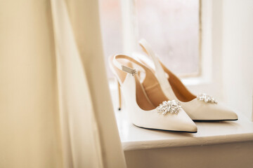 Beautiful bridal fashionable wedding white high heels shoes on a window at home.  Wedding