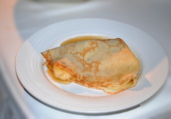 Finger banana flambe with crepes on a white plate.