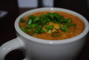 Cup of soup with slices of green onions on top.