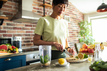 Young asian woman preparing healthy smoothie in home kitchen