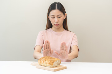 Gluten allergy, asian young woman hand push out, refusing to eat white bread loaf on board in...
