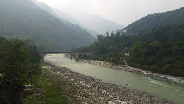 Aerial view above the Tista river, in a valley between mountains and Indian forest, on a sunny day, in Sikkim, India.