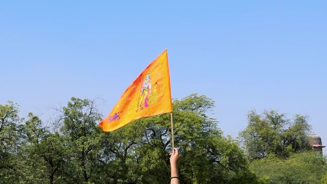 holy saffron flag with lord rama idol holing in hand with bright blue sky background at day