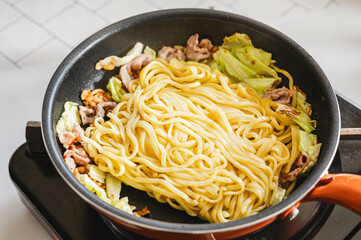 焼いた具材に麺を入れる