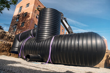 Attenuation tank made of big diameter plastic pipe delivered on construction site, offloaded and...