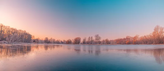 Muurstickers Calm lake water reflections forest trees panoramic sunrise sky. Beautiful silence morning dawn in early spring late winter. Soft bright pink purple colored sky panorama. Beautiful nature landscape © icemanphotos