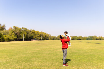father holding son in hand at outdoor with bright blue sky at morning