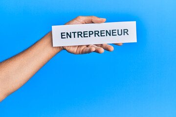Hand of caucasian man holding paper with entrepreneur word over isolated blue background