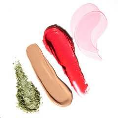 Textures of lipstick, foundation, eye shadow and eye patches on a white background.