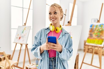Young caucasian woman artist using smartphone standing at art studio