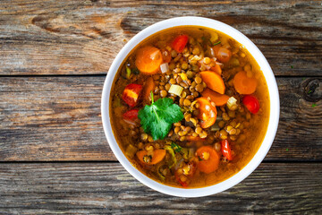 Fresh vegetable soup with lentil on wooden table

