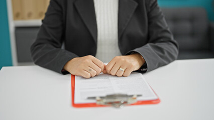 Young beautiful hispanic woman business worker sitting on table with documents at the office