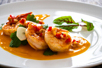 Shrimps salad with ginger and chili in mango sauce on wooden table
