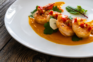 Shrimps salad with ginger and chili in mango sauce on wooden table
